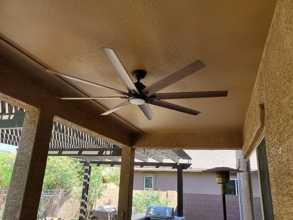 Covered patio with modern ceiling fan, stone columns, and pergola attached to residential home