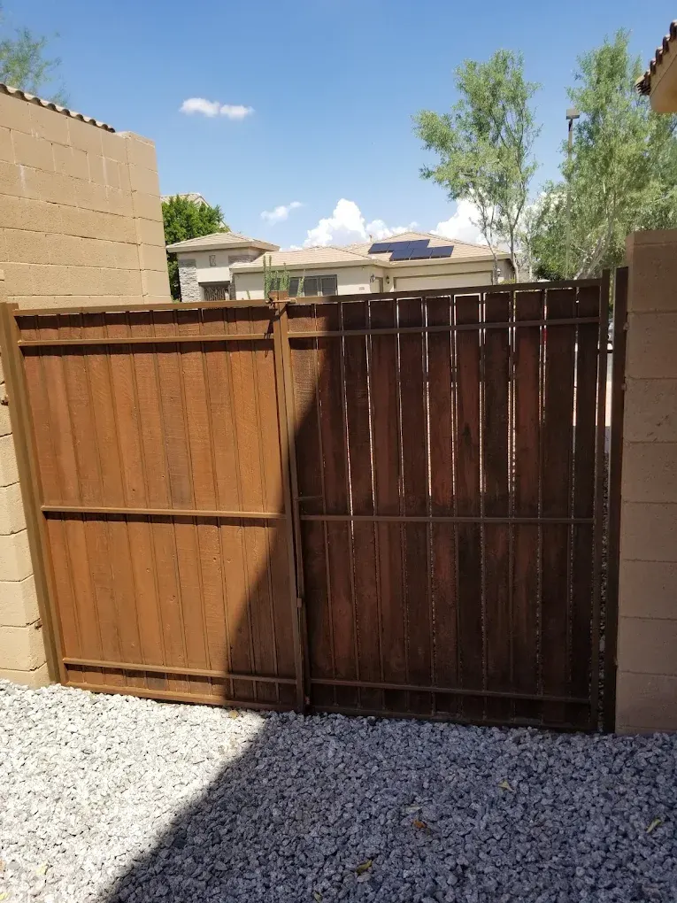 Two wooden gates in different stains flanking a residential driveway entrance